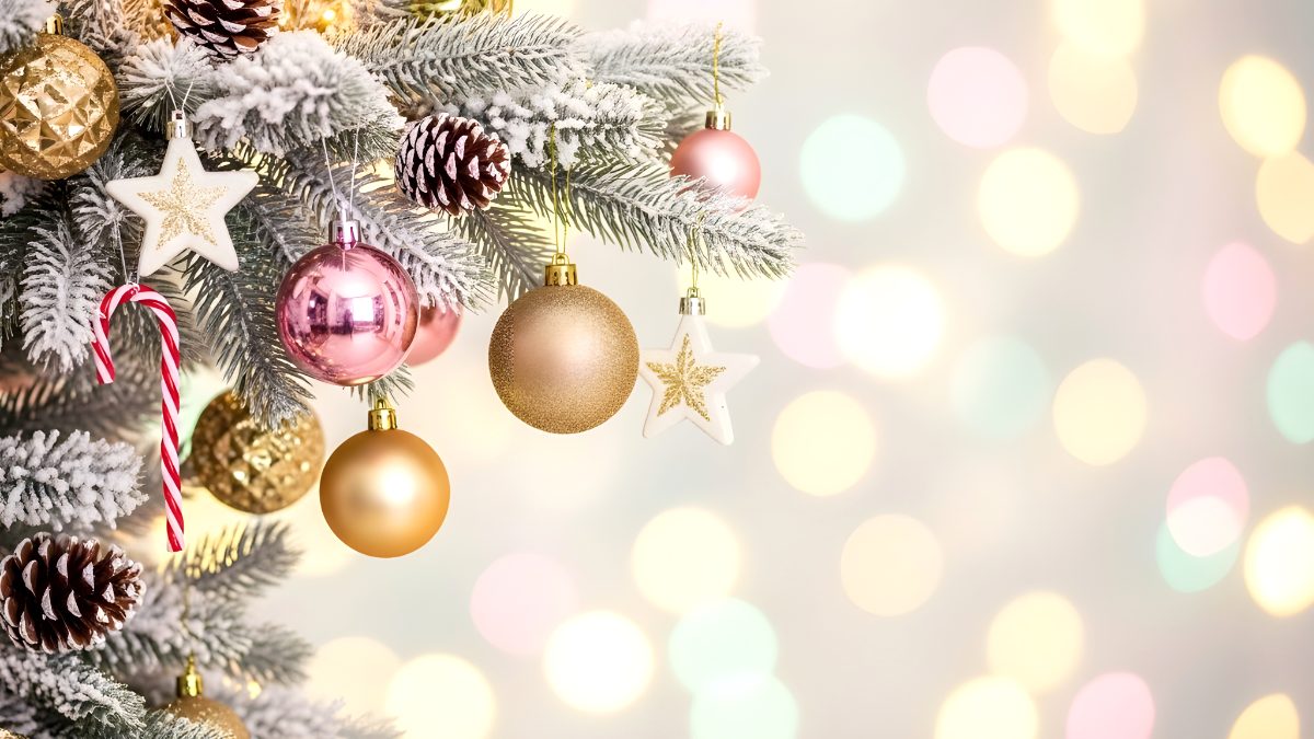Decorated christmas tree branches with gold and pink ornaments and candy cane against bokeh lights stock photo