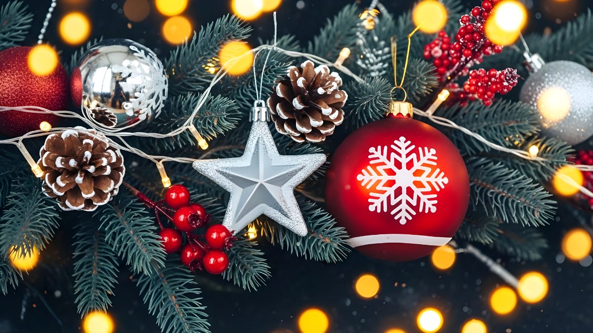 Christmas tree branches decorated with red and silver ornaments and glowing fairy lights stock photo