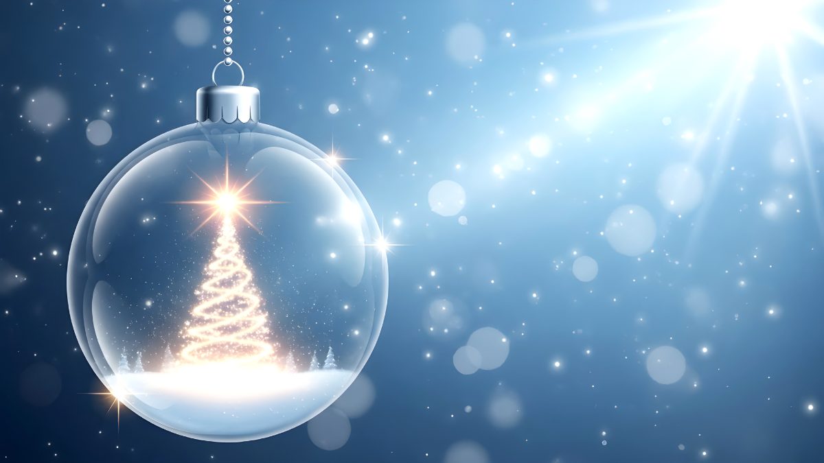 Transparent christmas bauble with glowing tree inside against blue bokeh background stock photo